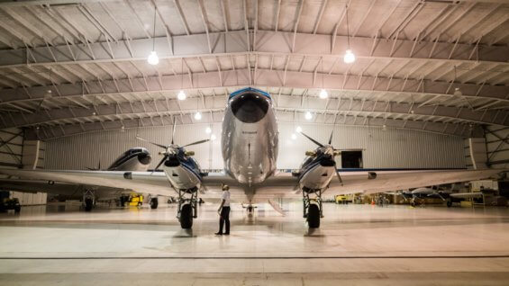 A man inspects an airplane in an airplane hanger.