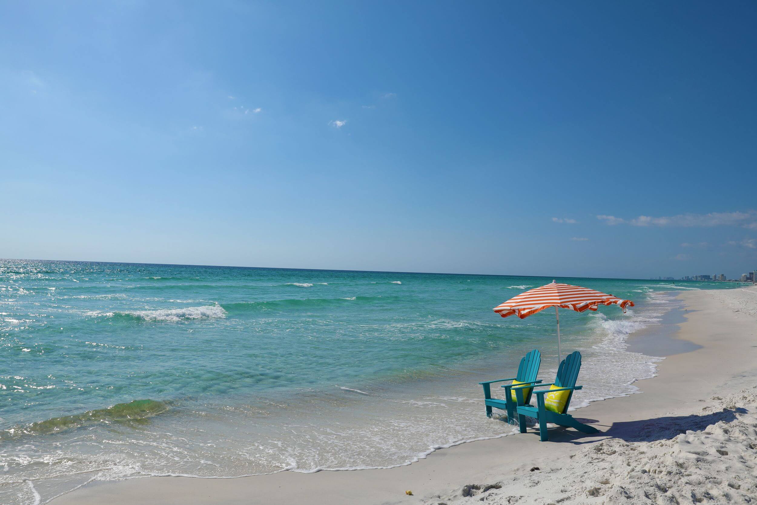 Two blue chairs on a white sand beach in Bay County.