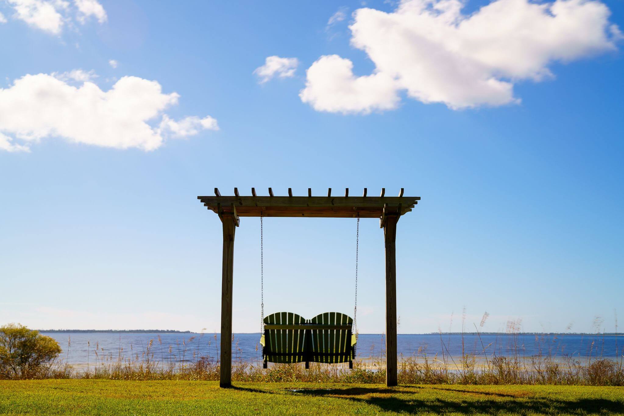 A light green swing bench overlooking a bay.
