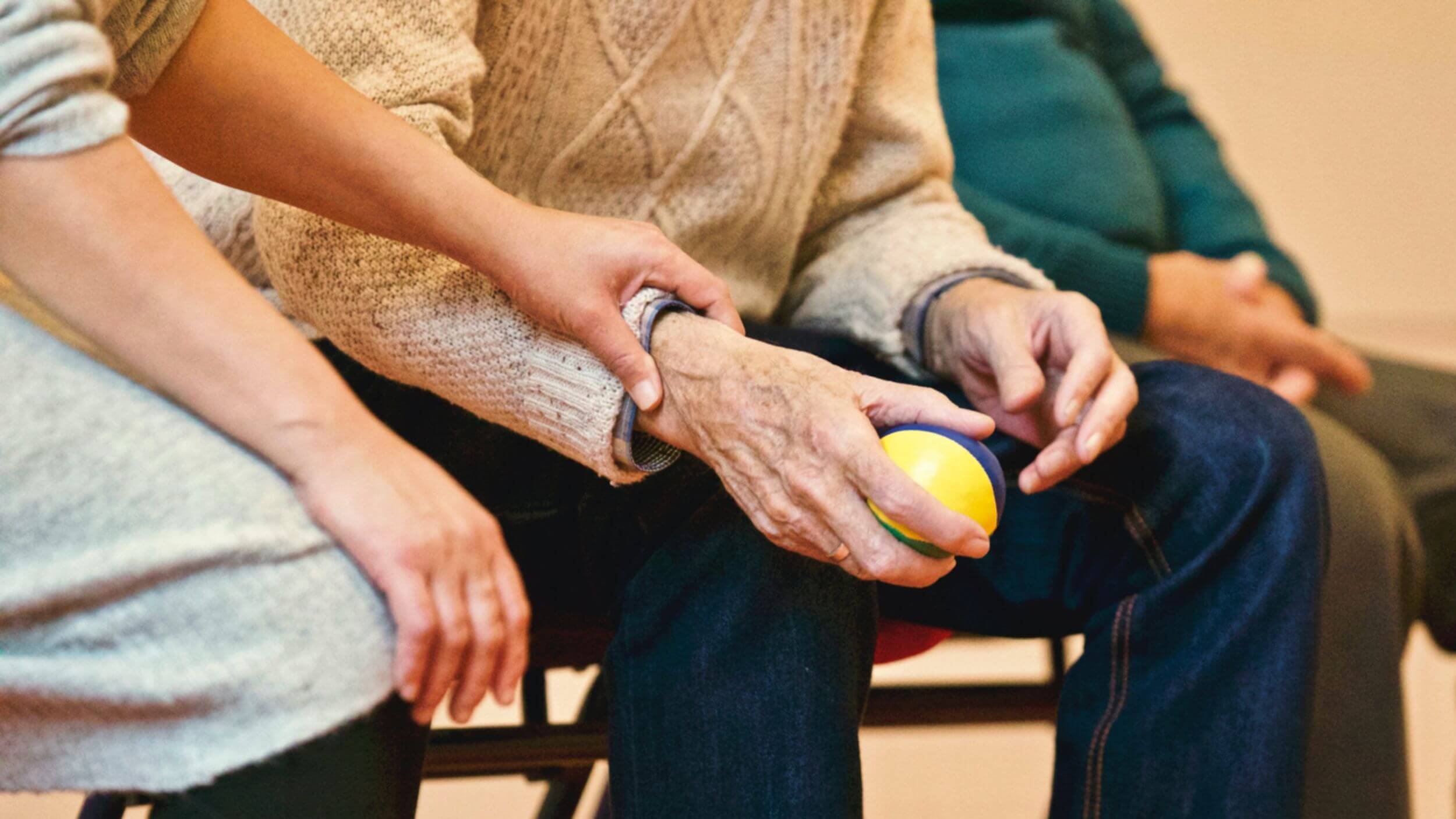 Older person holding hand exerciser ball.
