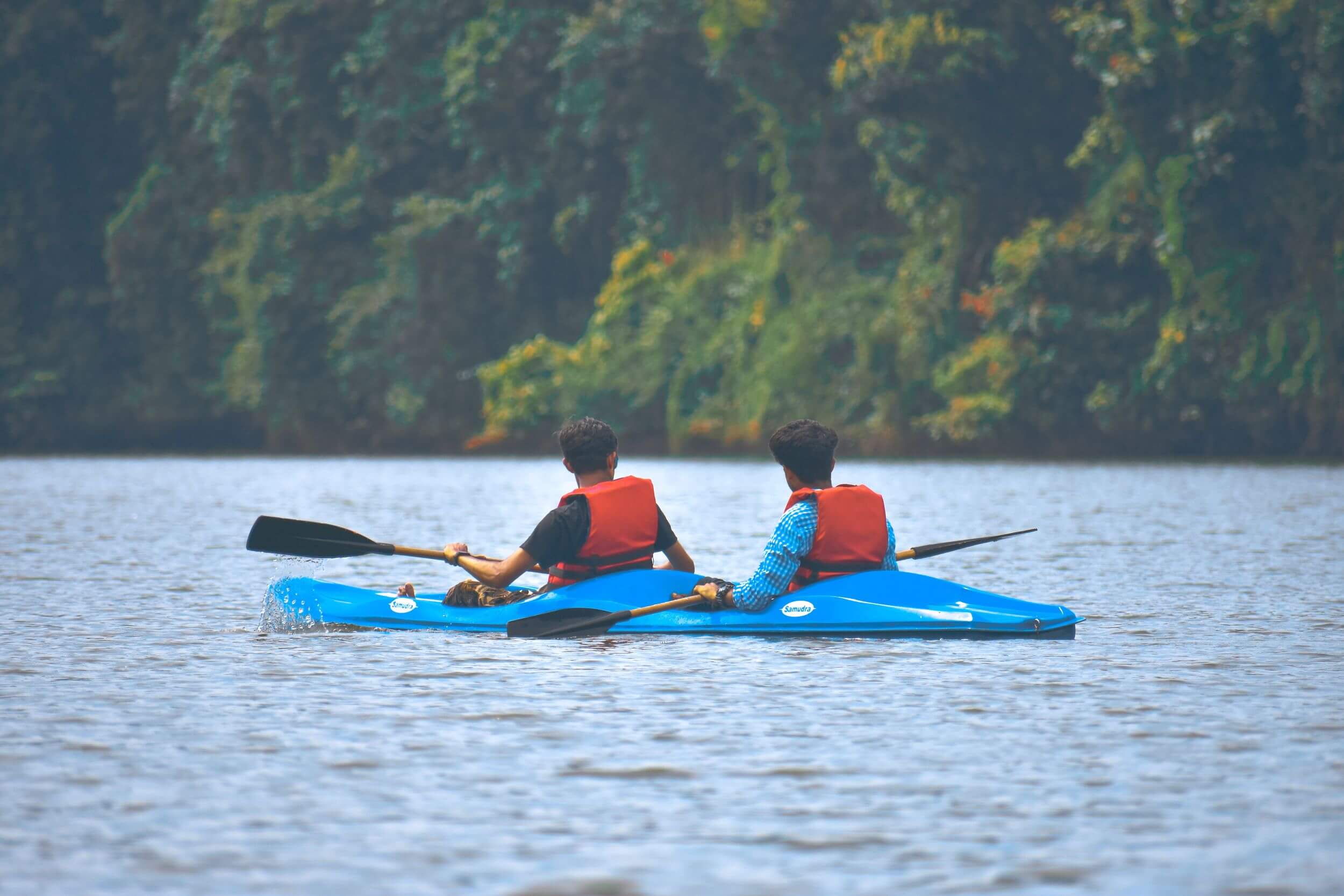 Two men kayak down a river.