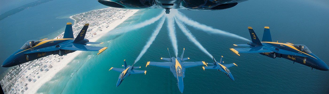 5 navy airplanes fly above a Pensacola beach.