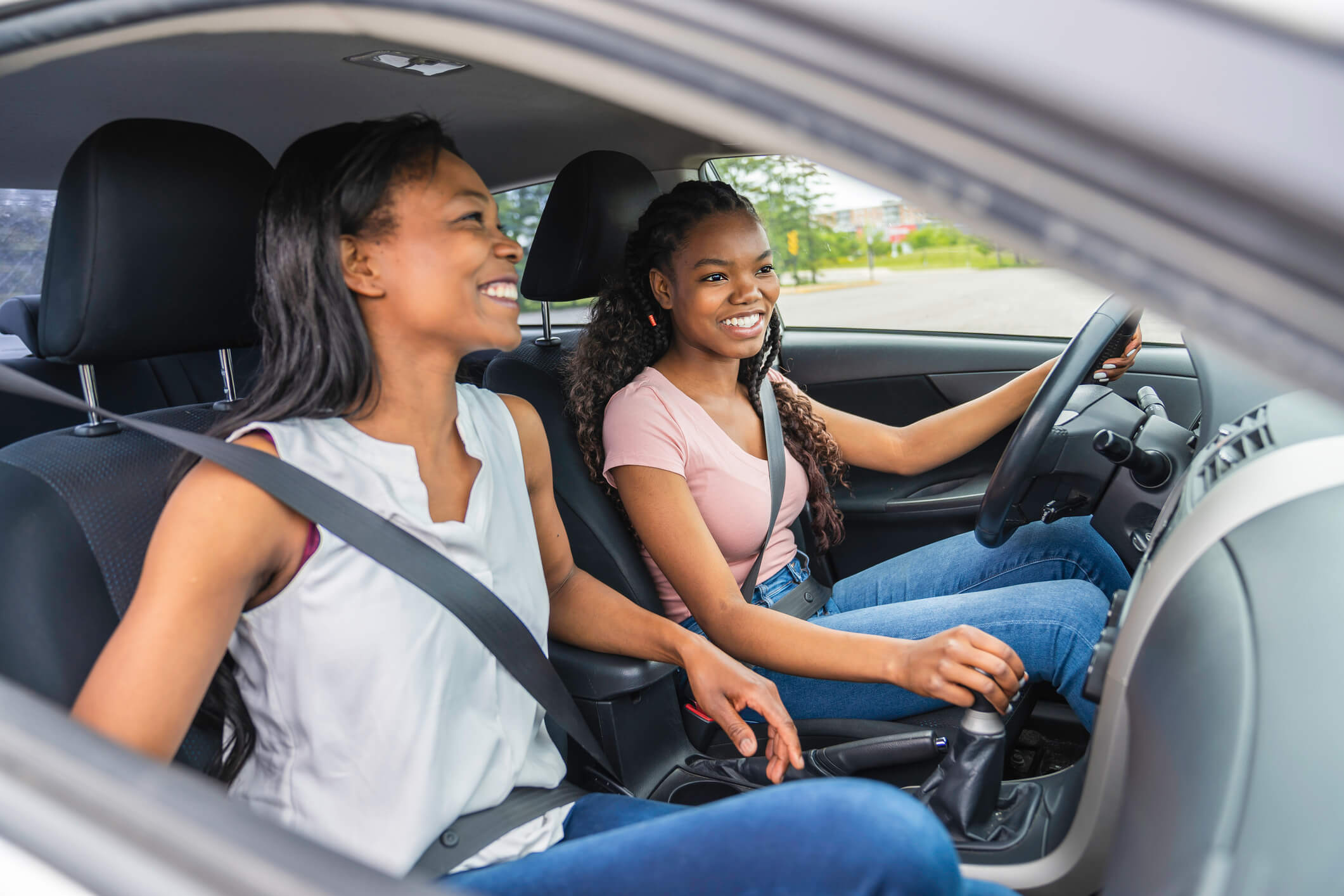 Two teenage girls driving happily in their car.