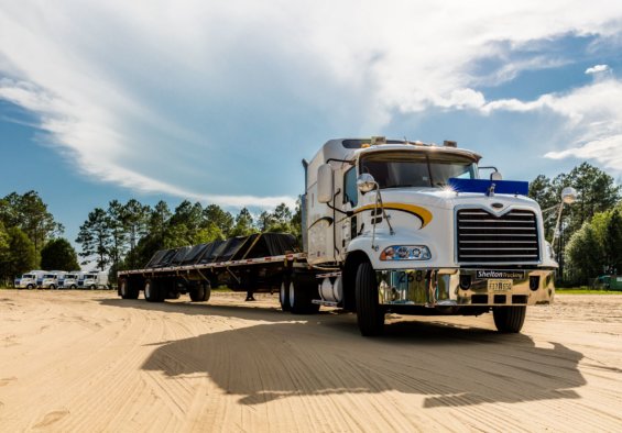 A Shelton Trucking vehicle pulls a long trailer.