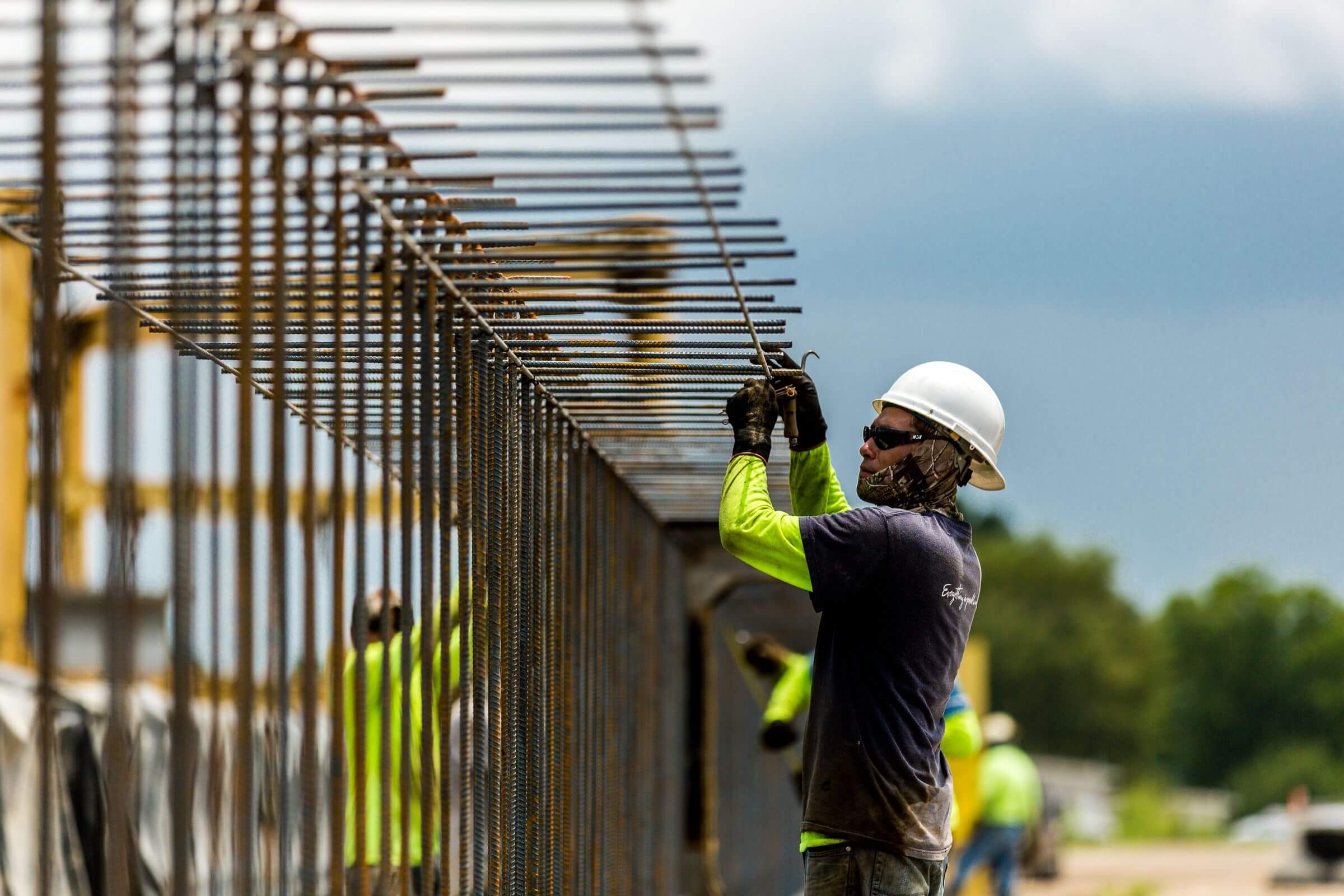 A man in a construction worker uniform fixes a fence.