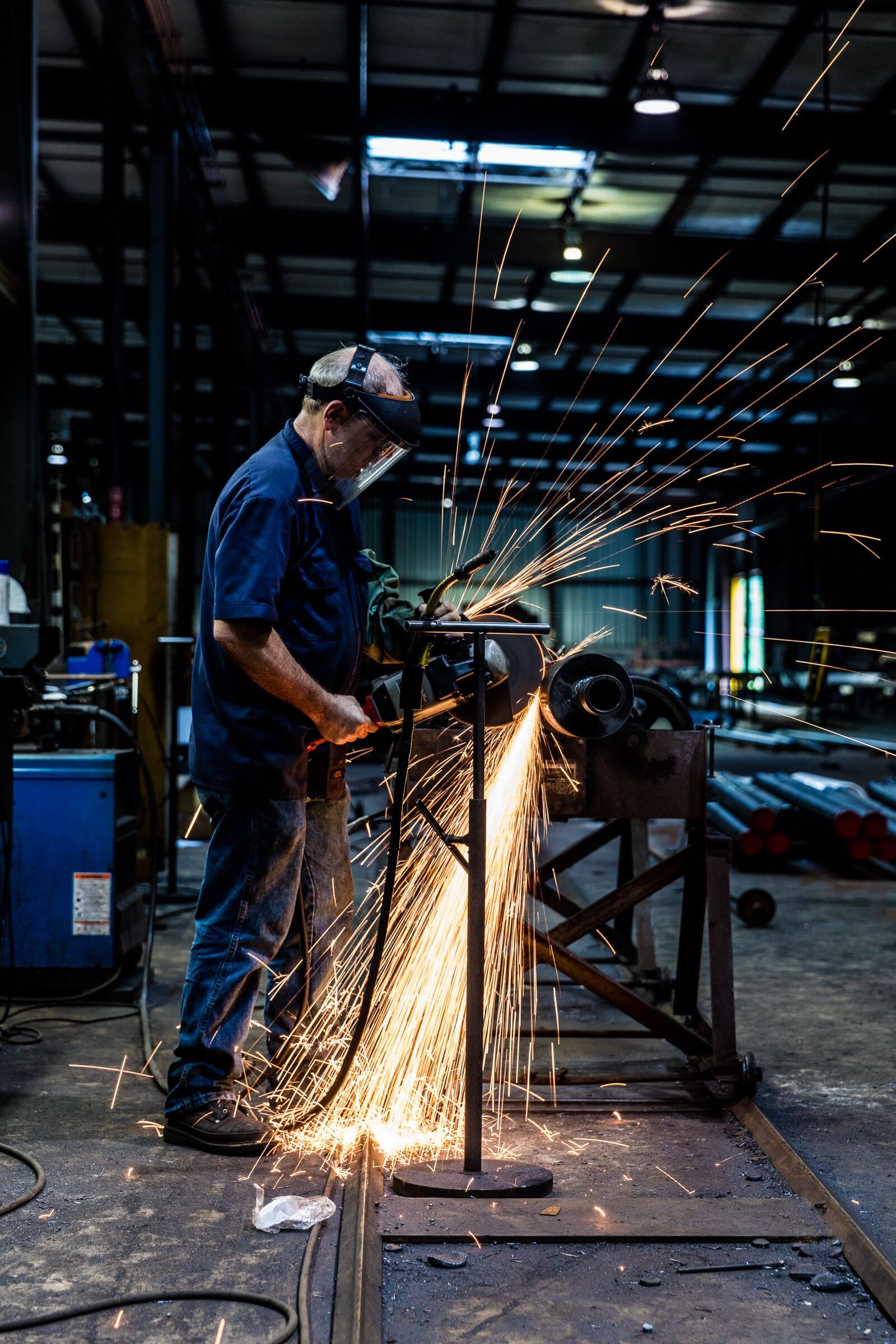 A person wearing a protective mask welds a piece of metal.
