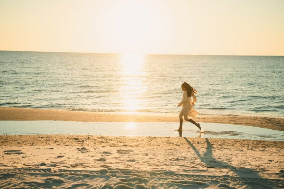 Woman runs along ocean shoreline.